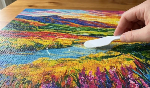 How to Glue a Puzzle: The Best Way to Seal and Preserve It 2 Using a spreader to evenly apply puzzle glue across the surface